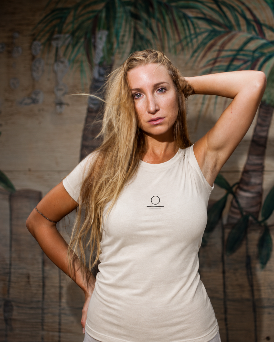 Harmonie wearing the Son of Nature S.O.N. emblem tee in ivory, charcoal sun-over-water mark on the chest, golden-hour Kauai