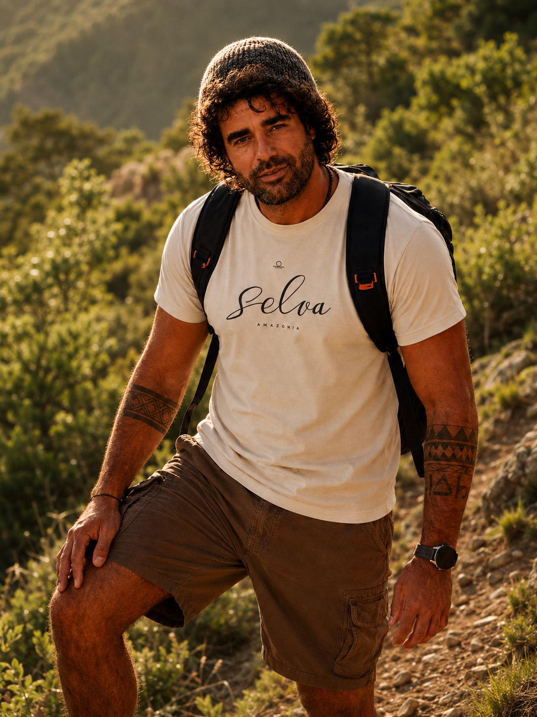 Man on a mountain ridge at golden hour in the Son of Nature Selva signature tee, charcoal Selva Amazonia lockup